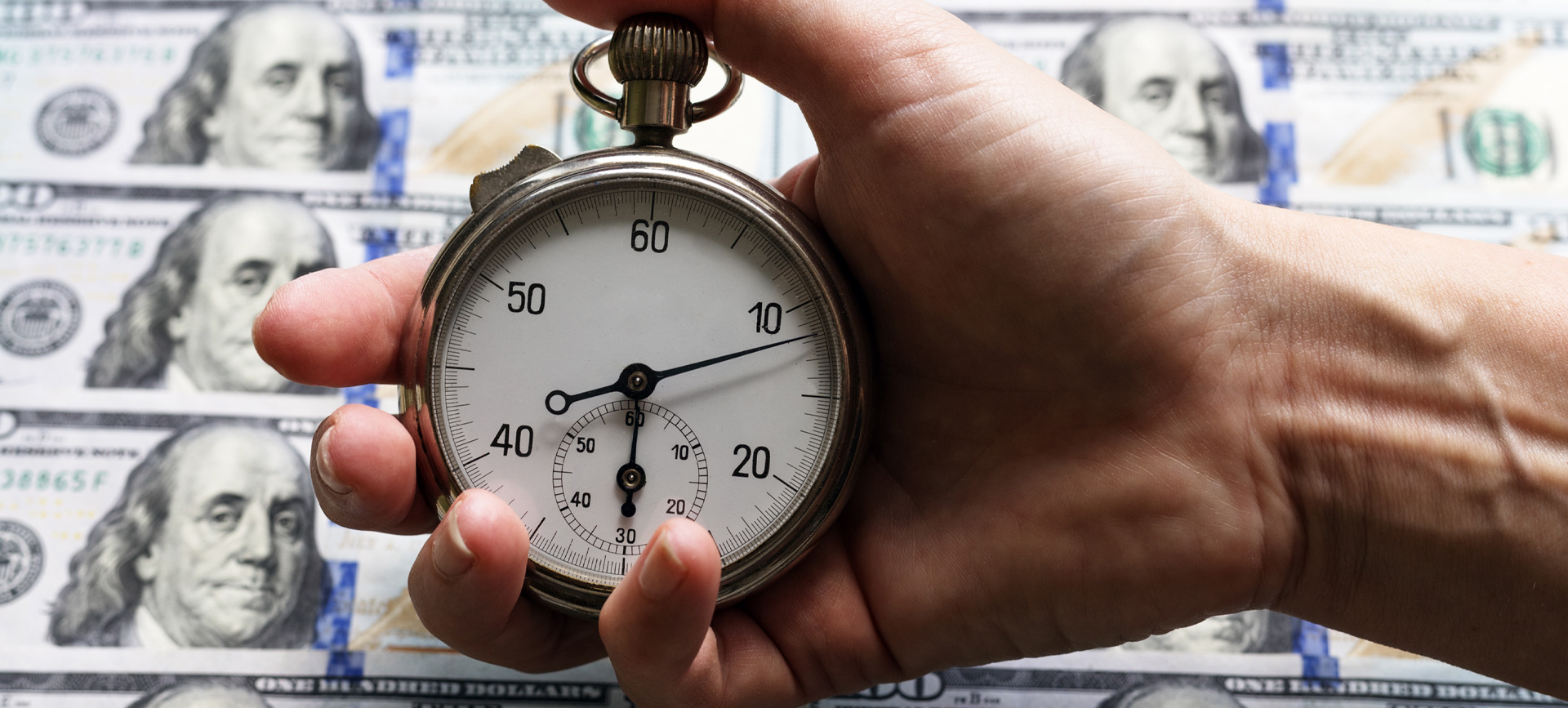 time-is-money-concept-stopwatch-hand-one-hundred-dollars-notes-as-background